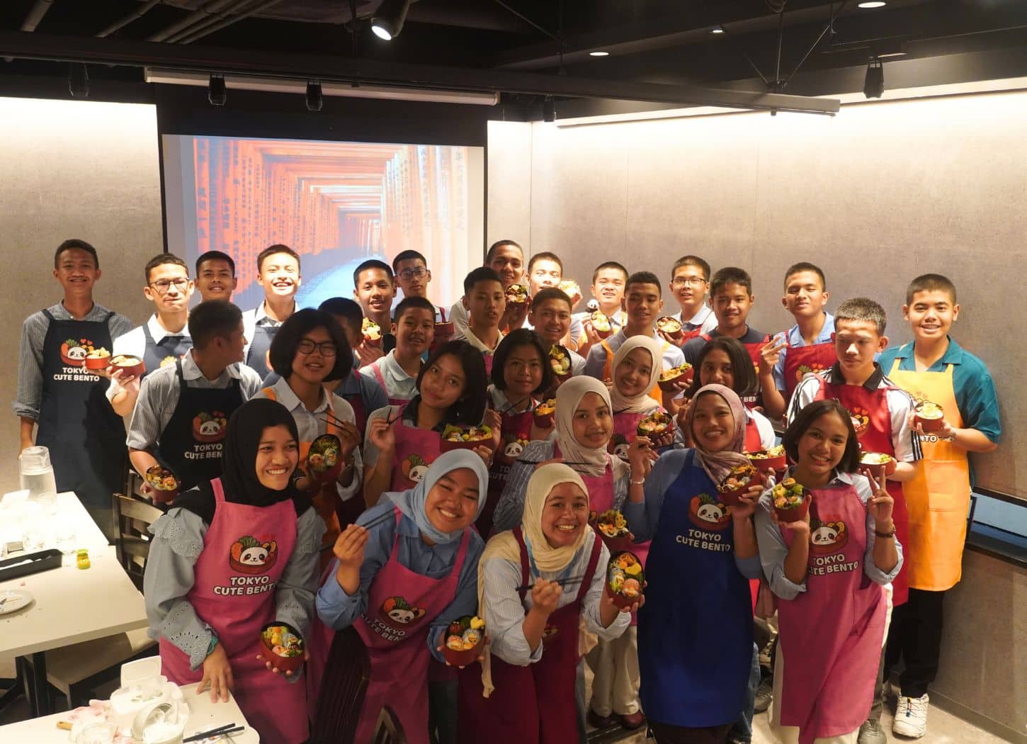 School trip students in aprons holding their finished character bento at Tokyo Cute Bento