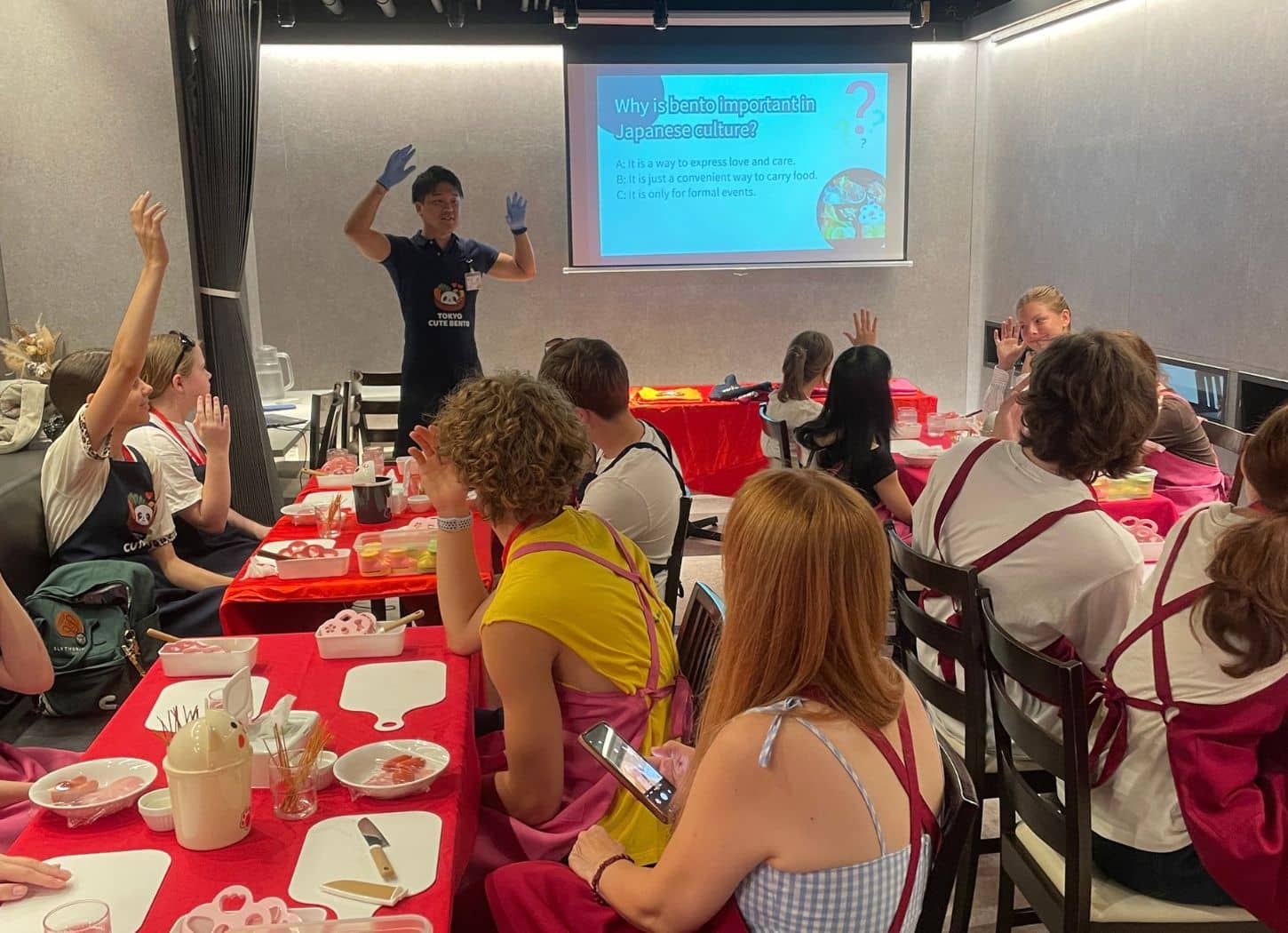 Group raising hands during an instructor-led bento culture quiz at Tokyo Cute Bento